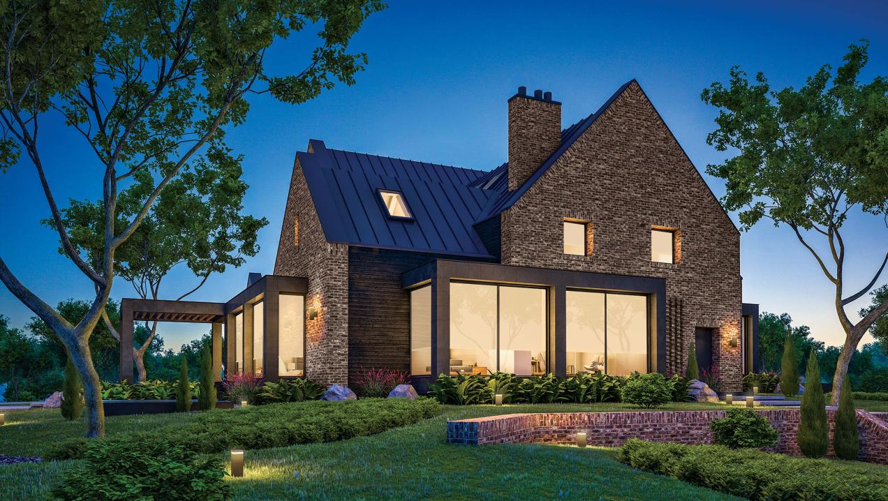 Grey-brick home at dusk with interior lights on.