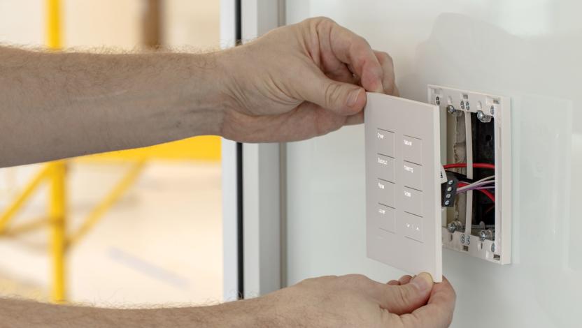 Electrician installing a Lutron keypad into a wall.
