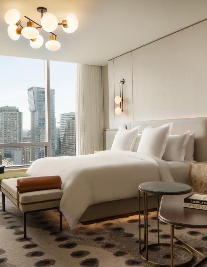Luxury hotel bedroom with skyline view of a city containing Lutron keypads.