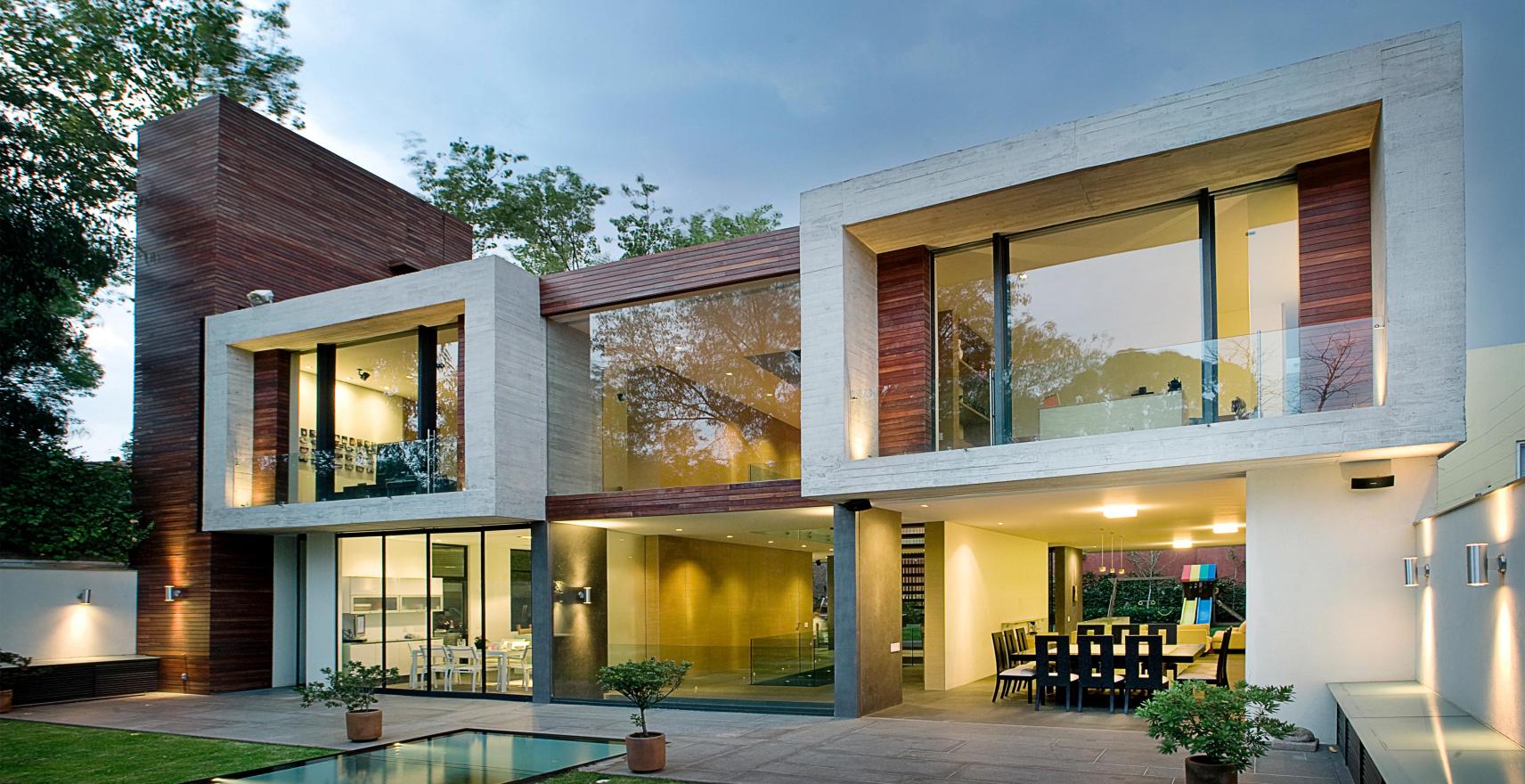 Contemporary two-story home with floor-to-ceiling windows and warm Lutron lighting at dusk. Photo by Jaime Navarro.