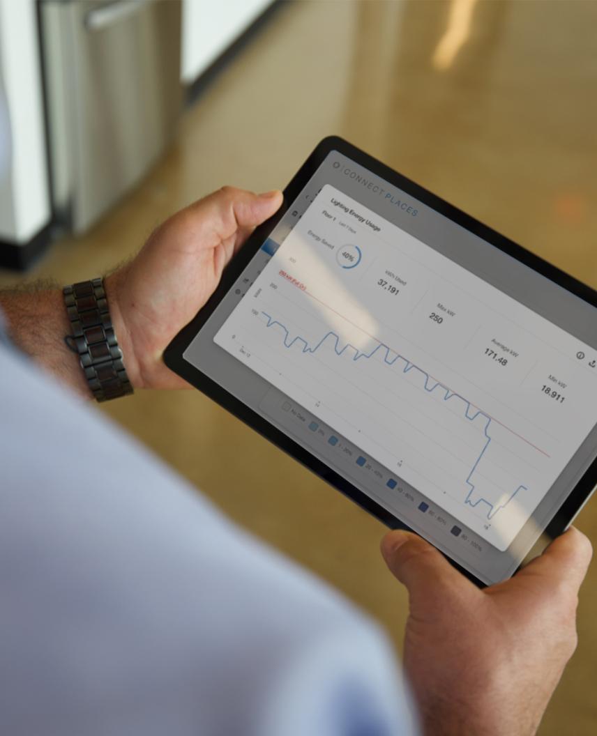 Tablet displaying building management dashboard with energy data graphs for centralized HVAC and lighting system monitoring 