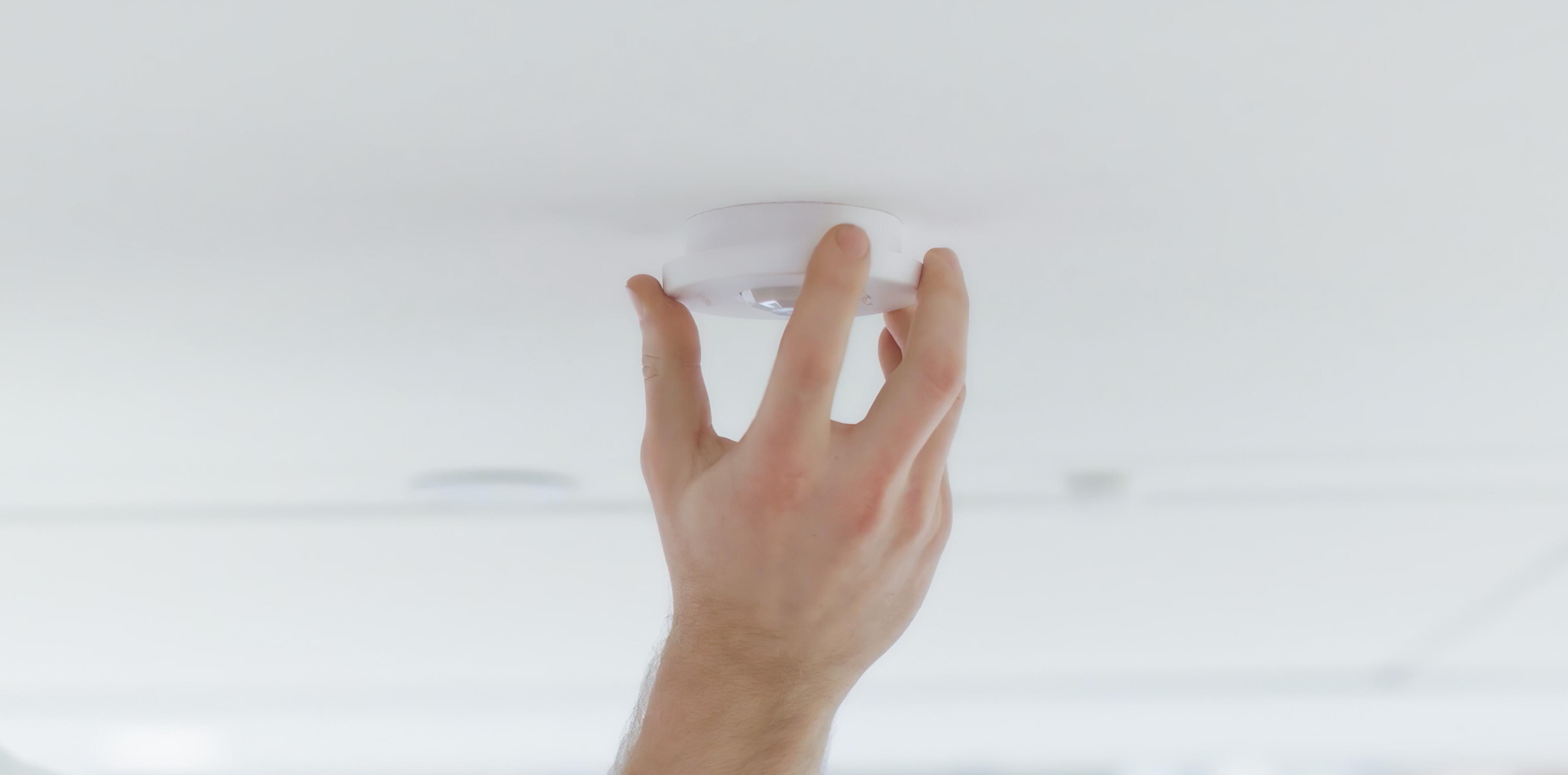Hand holding a Vive occupancy/vacancy sensor up to a ceiling.