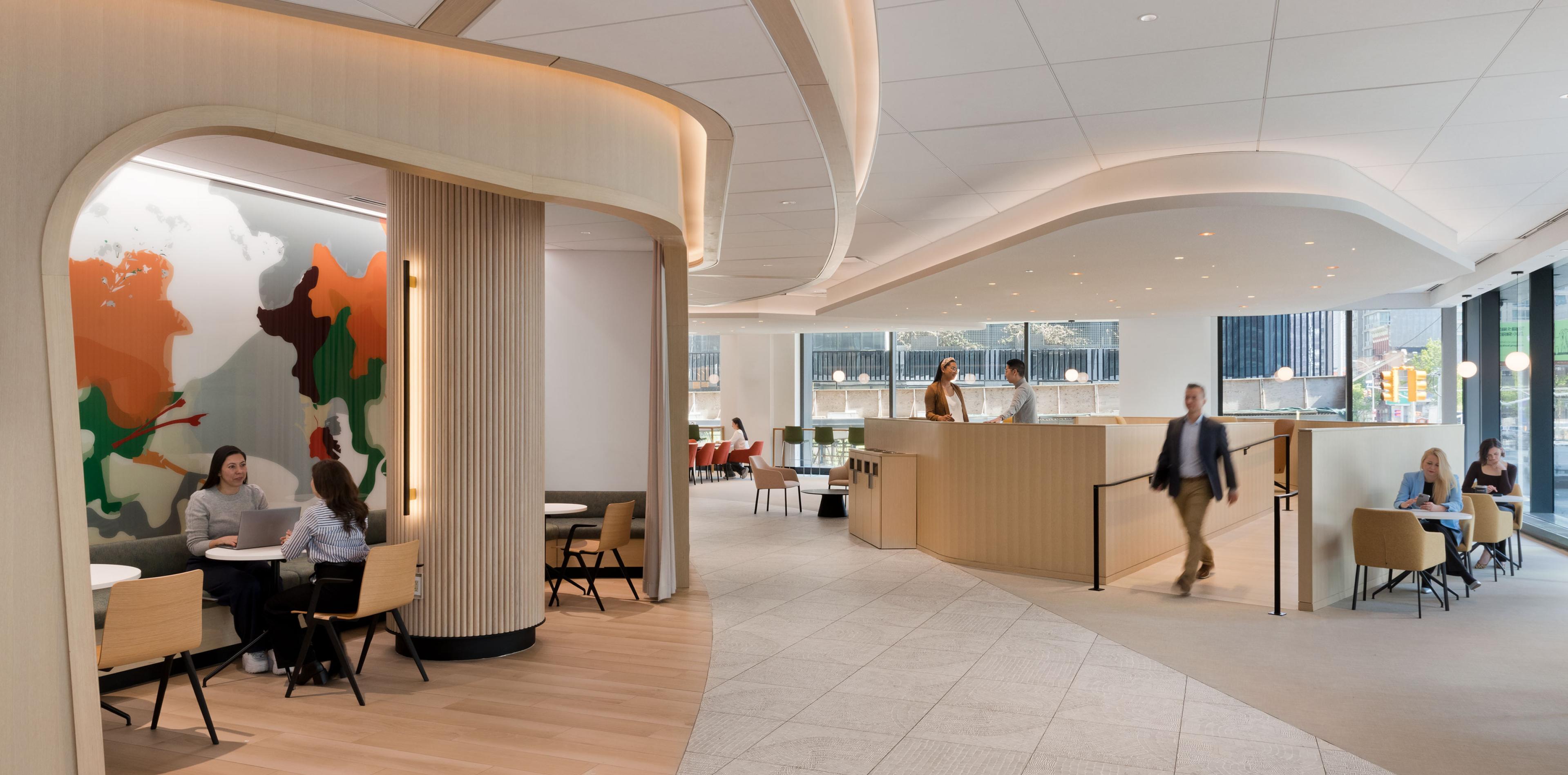 Office with curved architectural ceilings, booth seating with colorful artwork, and natural light throughout workspace.