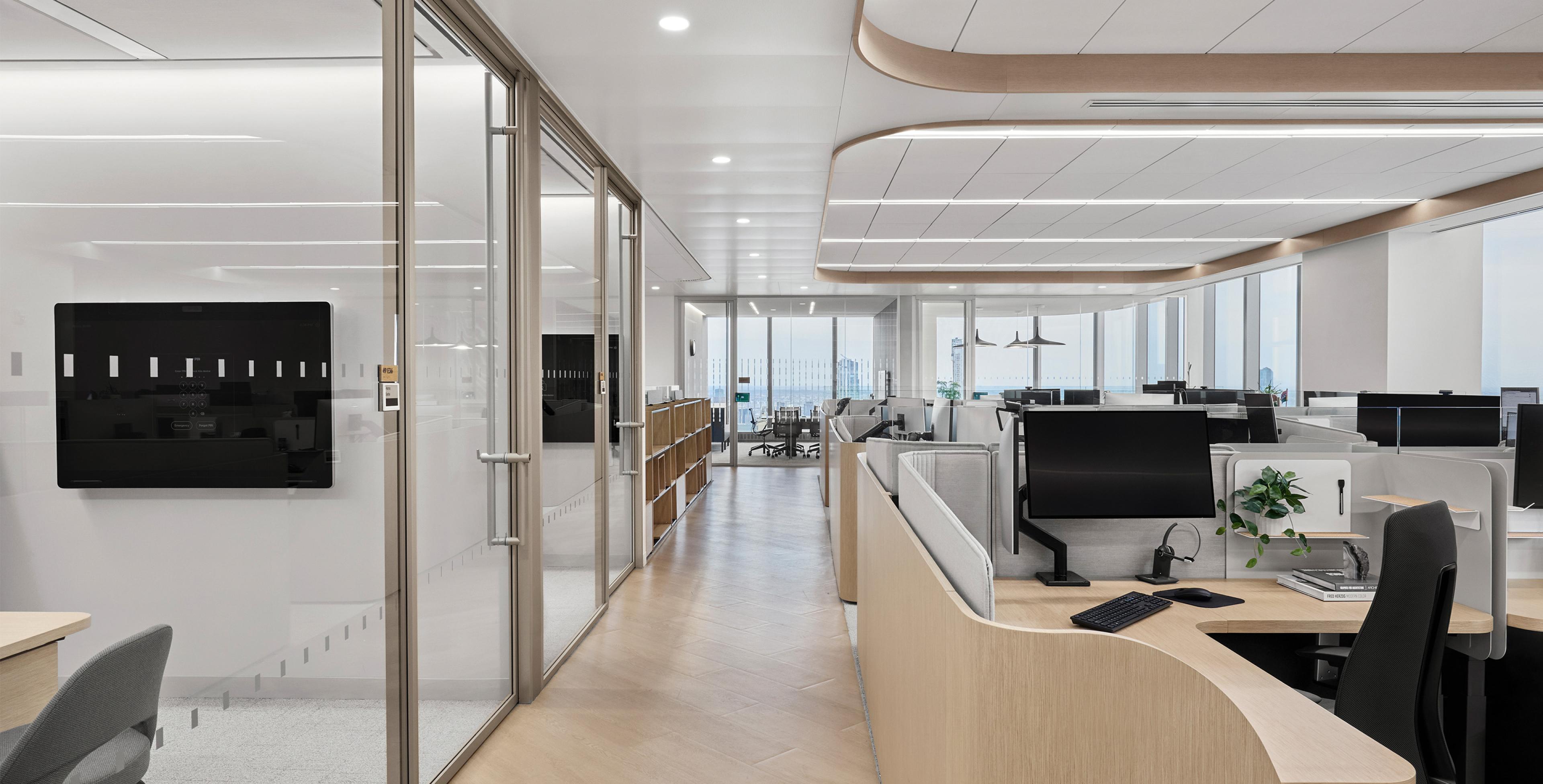 Open-plan office with curved workstations, automated window shades, integrated linear ceiling lighting, and glass-walled conference rooms overlooking city views 