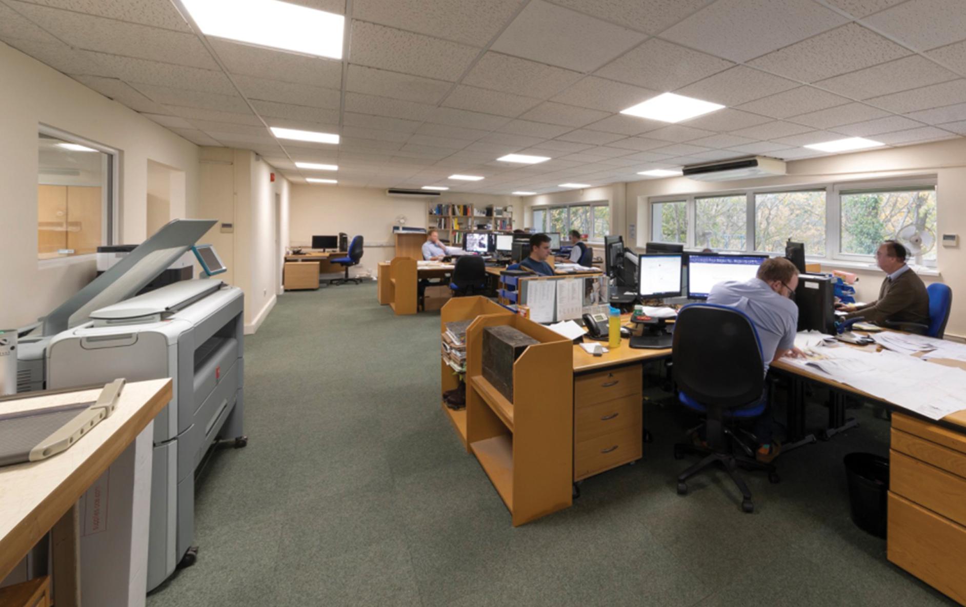 : Modern office with window views featuring Vive lighting control for code compliance.