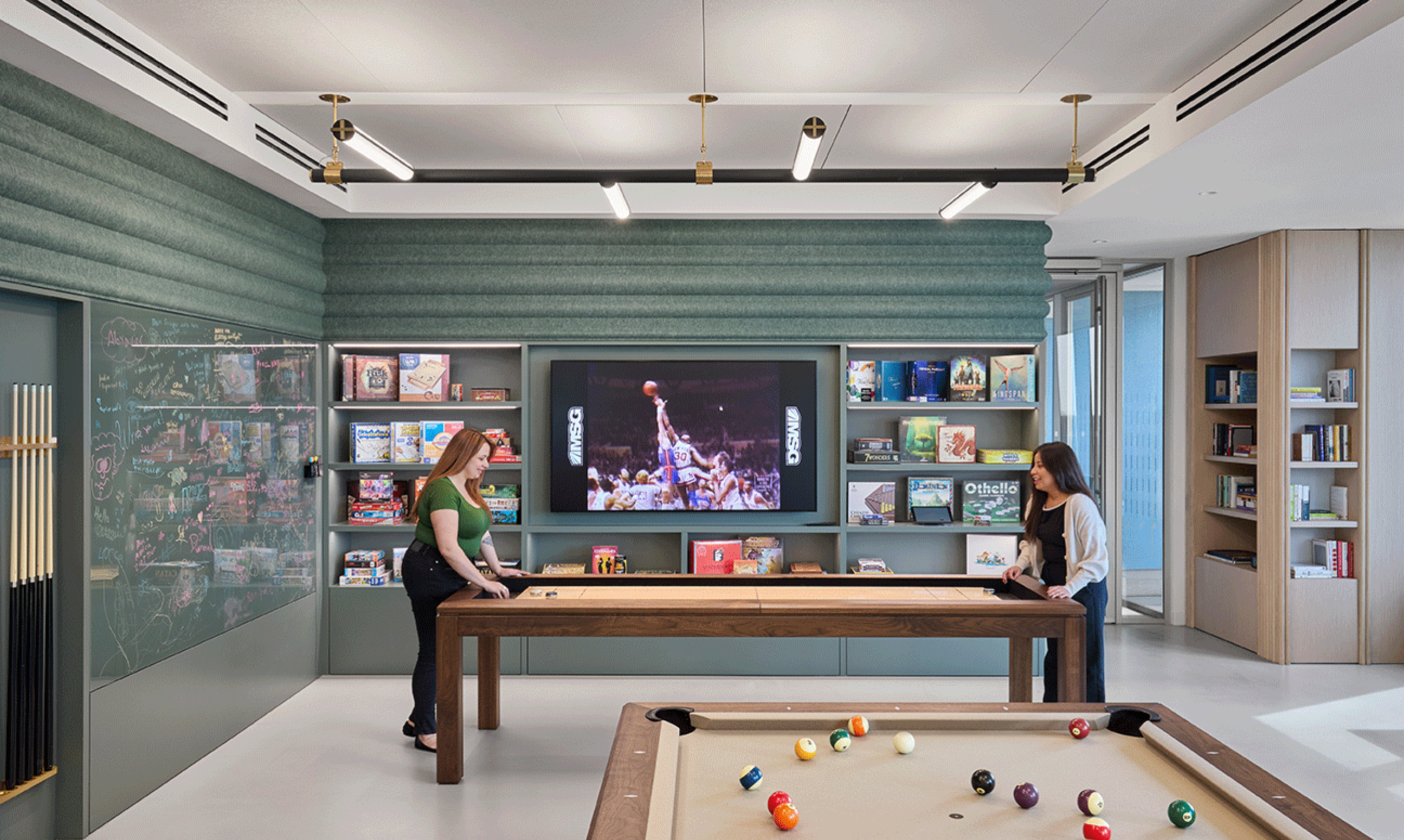 Two employees enjoy a game in an amenity room in a modern office