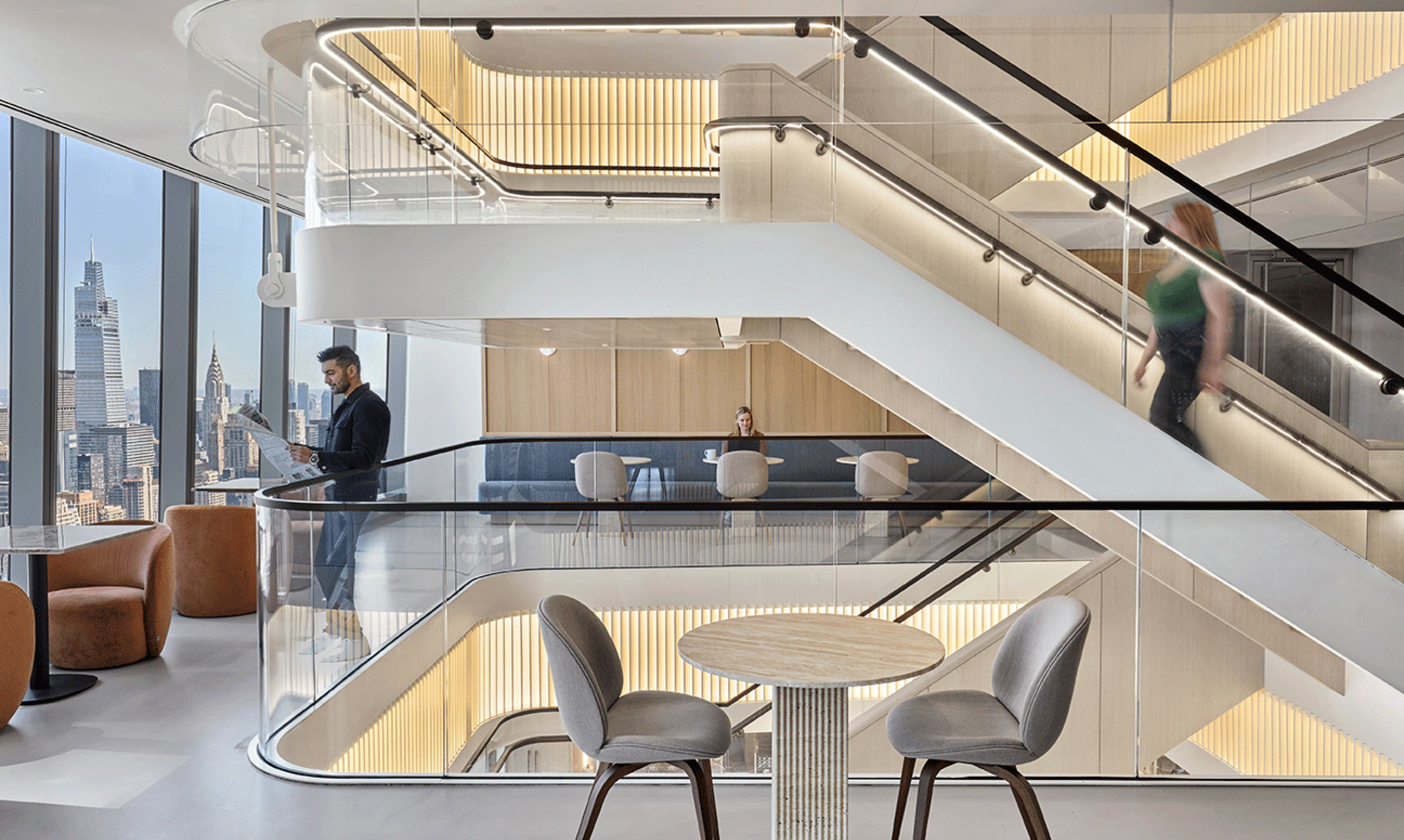 People enjoy the common space and central stair of a modern office building
